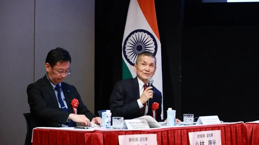 The Miyagi Vice Governor speaking into a microphone at a panel table beside the Indian flag.