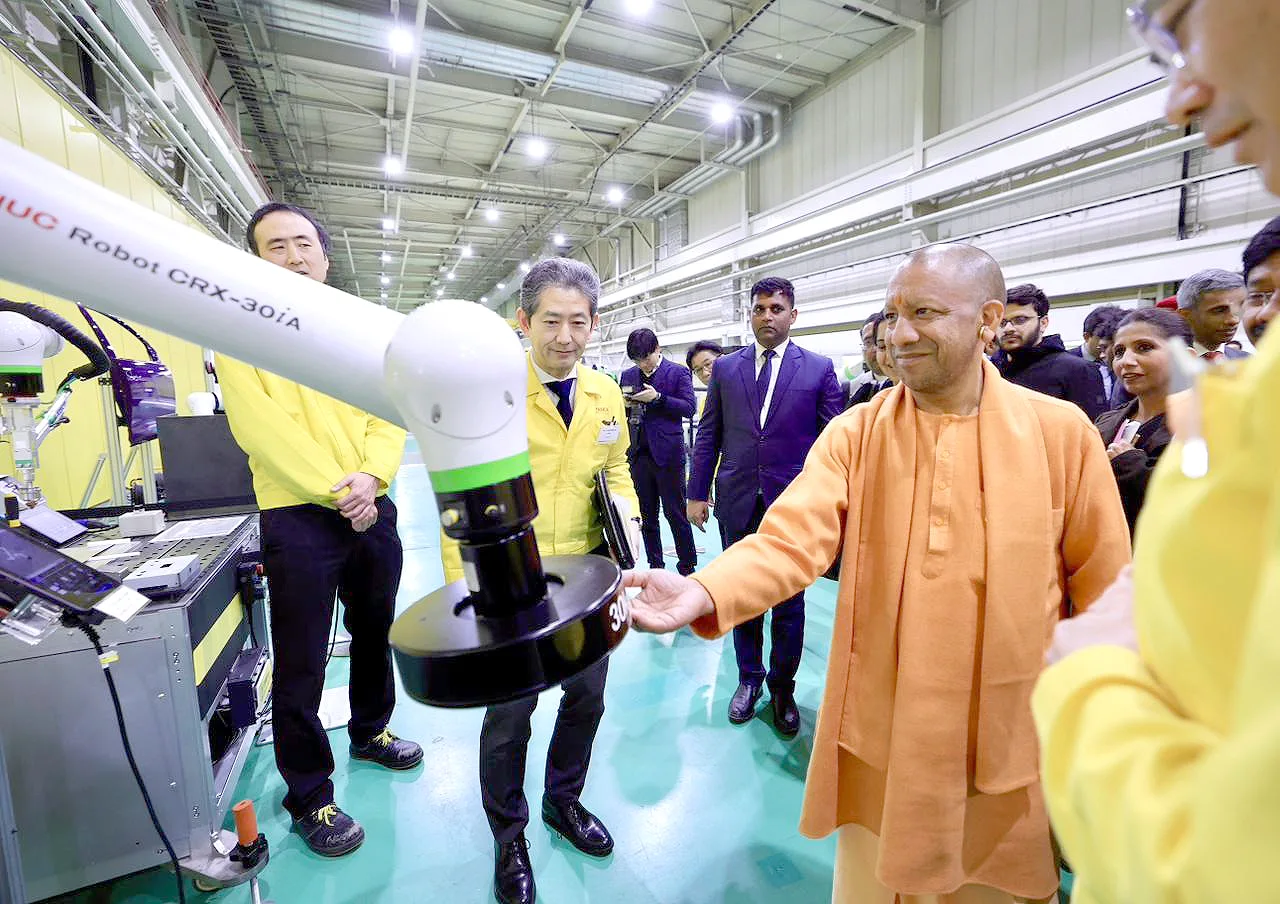 Chief Minister Yogi Adityanath inspecting a collaborative robot arm at a Japanese robotics facility.